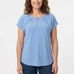 Front view of a woman wearing a light blue short-sleeve knit top with gold grommet-accented gathered neckline and keyhole
