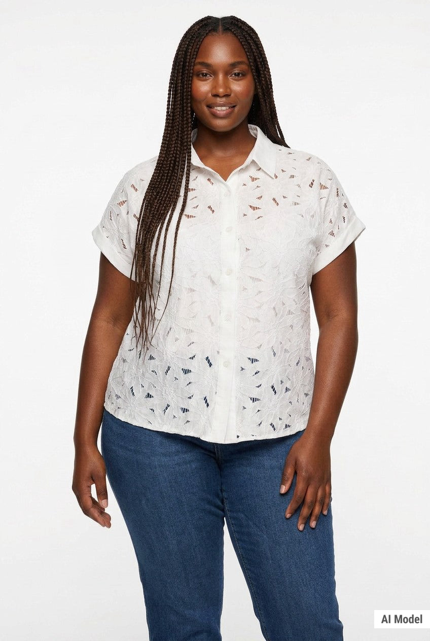 Plus-size model wears a white short-sleeve eyelet button-front blouse with floral cutwork detail; front view, waist up.