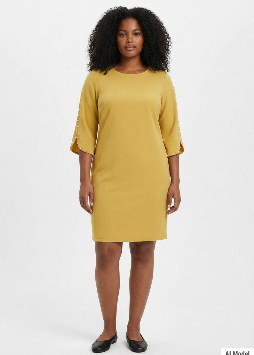 Plus-size model wears a mustard yellow sheath dress with 3/4 petal sleeves trimmed with pearl details and a round neckline,