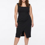 Plus-size model wears a black sleeveless square-neck sheath dress with a front wrap slit and high-waist band; front view.