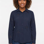 Navy long-sleeve button-front blouse with cutwork palm tree embroidery, worn by a curly-haired woman, front view, waist up.