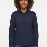 Navy long-sleeve button-front blouse with cutwork palm tree embroidery, worn by a curly-haired woman, front view, waist up.