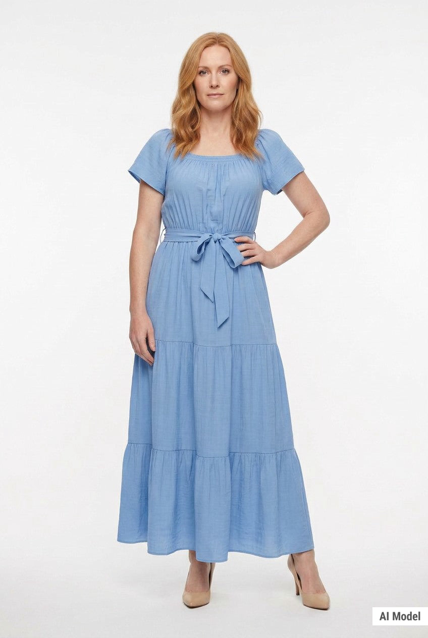 Redhead woman wearing a light blue short-sleeve tiered maxi dress with square neckline and tie waist belt; front view.