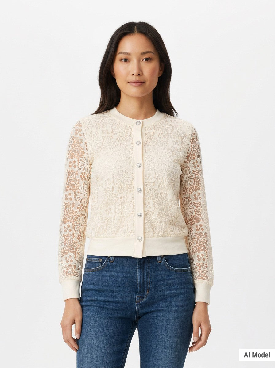 Woman wearing a cream floral lace cardigan with sheer sleeves, jewel buttons, and ribbed trim, paired with blue jeans, front