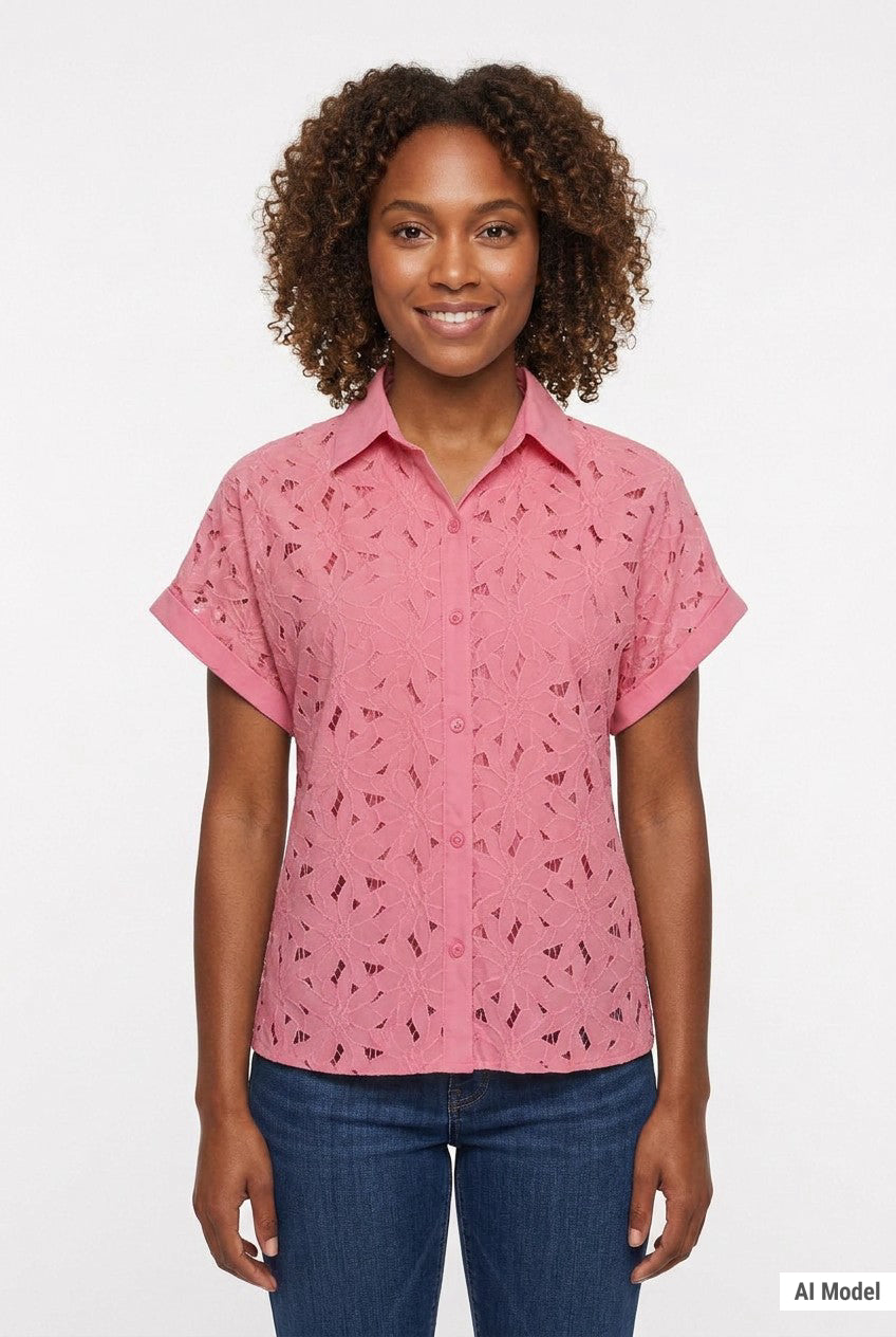 Woman wearing a pink short-sleeve eyelet button-front blouse with collar and cuffed sleeves, paired with dark jeans; front